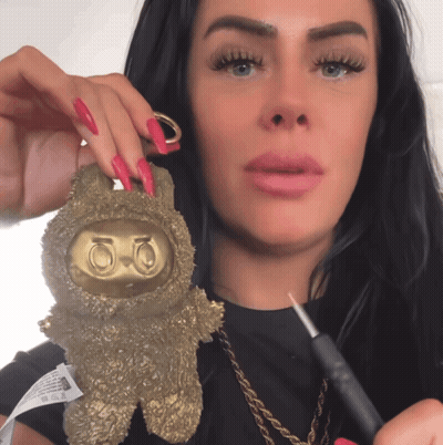 A Woman With Long Red Nails Is Holding A Gold Keychain With The Number 50 On It GIF