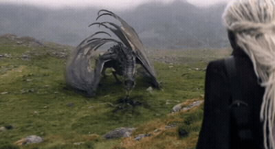 A Woman With Long White Hair Stands In Front Of A Dragon GIF
