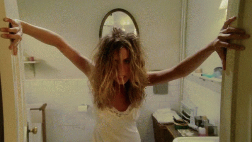 A Woman With Messy Hair Is Standing In A Bathroom GIF