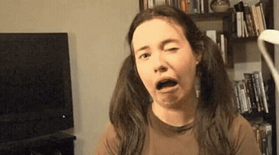 A Woman With Pigtails Is Making A Funny Face While Sitting In Front Of A Television . GIF