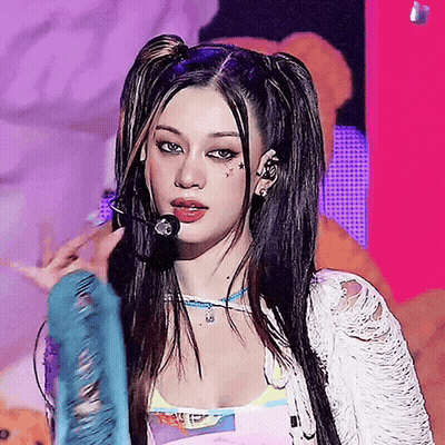 A Woman With Pigtails Is Singing Into A Microphone On A Stage GIF
