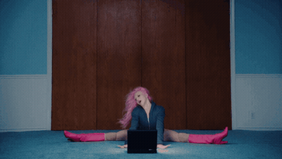 A Woman With Pink Hair And Blue Shorts Is Laying On The Floor GIF