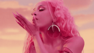 A Woman With Pink Hair And Earrings Blowing A Kiss GIF