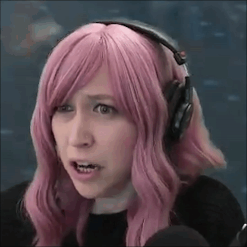 A Woman With Pink Hair And Headphones Is Making A Face . GIF