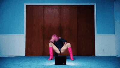 A Woman With Pink Hair And Pink Boots Is Kneeling On A Laptop GIF