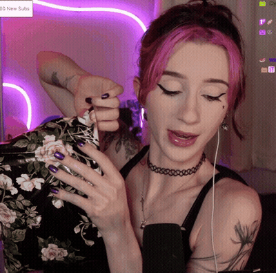 A Woman With Pink Hair And Purple Nails Is Playing A Game On A Screen That Says 100 New Subs GIF