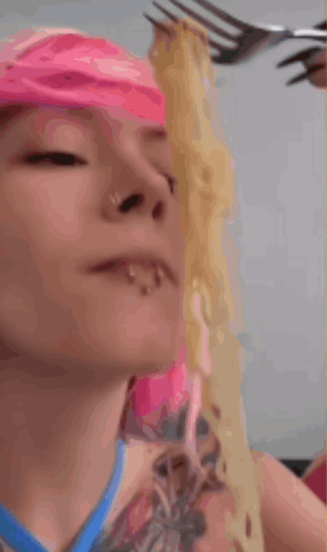 A Woman With Pink Hair Eats Noodles With A Fork GIF