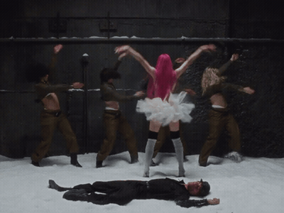 A Woman With Pink Hair Is Dancing In Front Of A Group Of Soldiers GIF