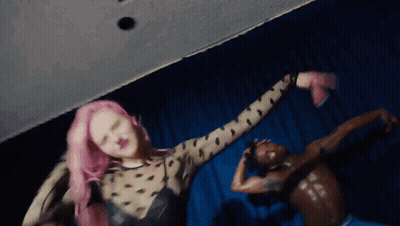 A Woman With Pink Hair Is Dancing Next To A Man With No Shirt On GIF