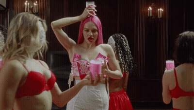 A Woman With Pink Hair Is Holding A Candle In Her Hand GIF