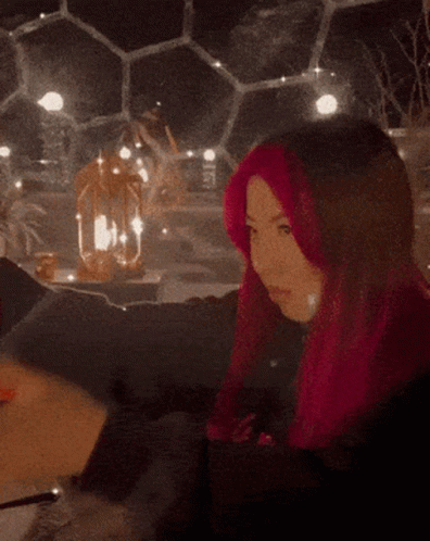 A Woman With Pink Hair Is Holding A Glass Of Water GIF