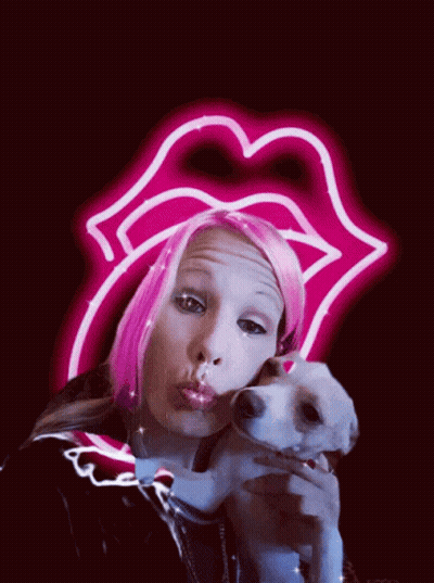 A Woman With Pink Hair Is Holding A Small Dog In Front Of A Neon Sign That Says Rolling Stones GIF