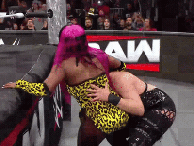 A Woman With Pink Hair Is Hugging Another Woman In Front Of A Raw Sign GIF