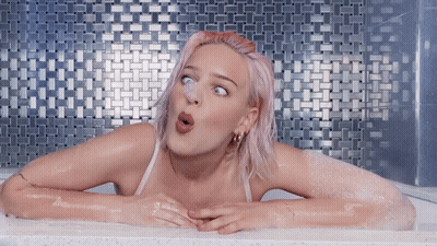 A Woman With Pink Hair Is In A Bathtub GIF