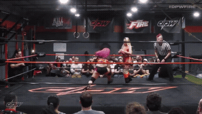 A Woman With Pink Hair Is In A Wrestling Ring With #Dpwfire Written Above Her GIF