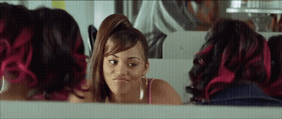 A Woman With Pink Hair Is Looking At Herself In The Mirror And Making A Funny Face . GIF
