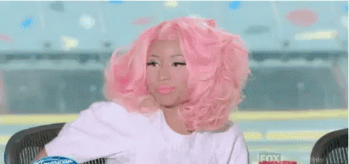 A Woman With Pink Hair Is Sitting At A Table With The Words Tutta Invidia Above Her GIF