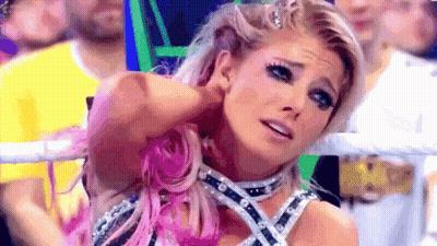 A Woman With Pink Hair Is Standing In A Ring With A Crowd Behind Her . GIF