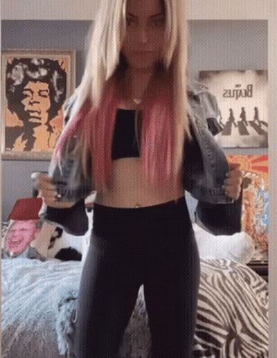 A Woman With Pink Hair Is Standing In Front Of A Poster That Says Jimi Hendrix GIF