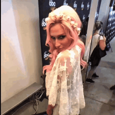 A Woman With Pink Hair Is Standing In Front Of A Wall With Abc On It GIF