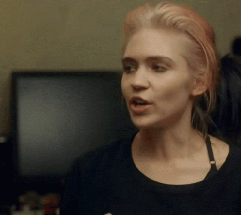A Woman With Pink Hair Is Wearing A Black Top GIF