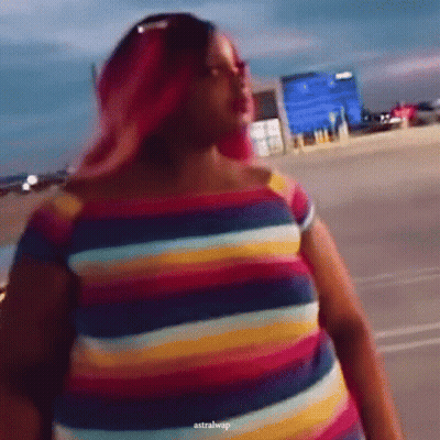 A Woman With Pink Hair Is Wearing A Colorful Striped Dress GIF