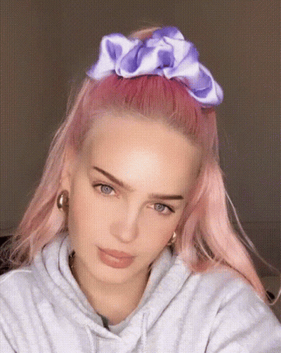 A Woman With Pink Hair Is Wearing A Purple Scrunchie In Her Hair GIF