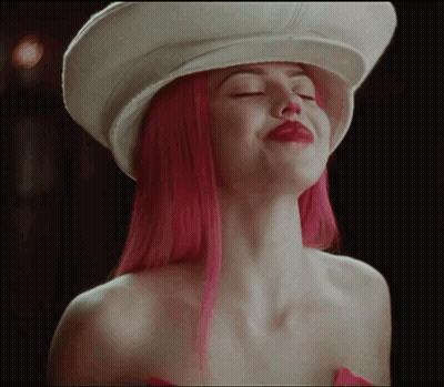 A Woman With Pink Hair Is Wearing A White Hat With Her Eyes Closed GIF