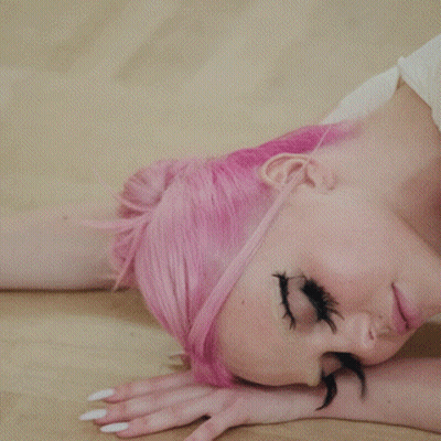 A Woman With Pink Hair Laying On The Floor GIF
