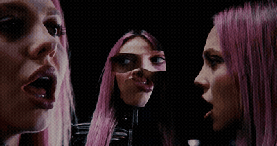 A Woman With Pink Hair Looks At Herself In The Mirror GIF