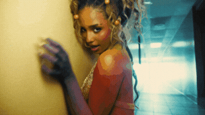 A Woman With Purple Gloves Is Standing In A Hallway And Looking At The Camera GIF
