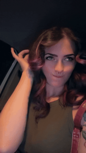 A Woman With Purple Hair And A Tattoo On Her Arm Looks At The Camera GIF