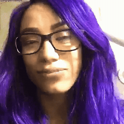 A Woman With Purple Hair And Glasses Makes A Funny Face . GIF