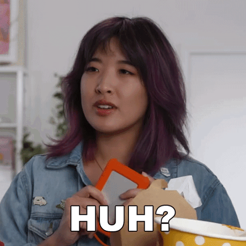 A Woman With Purple Hair Is Holding An Orange Box And Says Huh ? GIF