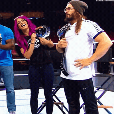 A Woman With Purple Hair Is Laughing Next To A Man Wearing Glasses GIF