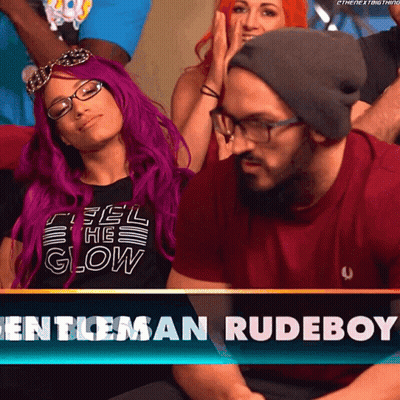 A Woman With Purple Hair Is Sitting Next To A Man Wearing Glasses And A Beanie GIF