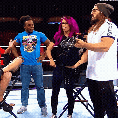 A Woman With Purple Hair Is Standing Next To A Man In A Blue Shirt That Says Booty On It GIF