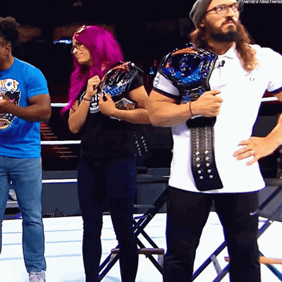 A Woman With Purple Hair Is Standing Next To A Man With A Beard Holding A Championship Belt GIF