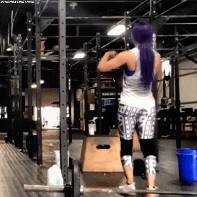 A Woman With Purple Hair Is Working Out In A Gym . GIF
