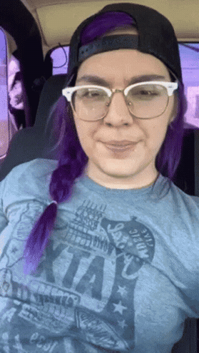 A Woman With Purple Hair Wearing Glasses And A T-Shirt That Says ' I Love Kansas ' On It GIF