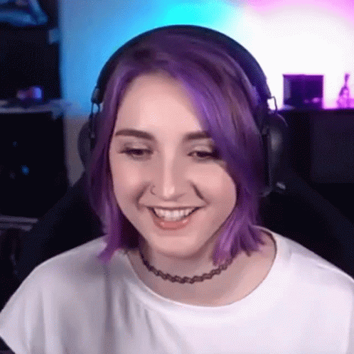 A Woman With Purple Hair Wearing Headphones And A Choker Is Smiling . GIF
