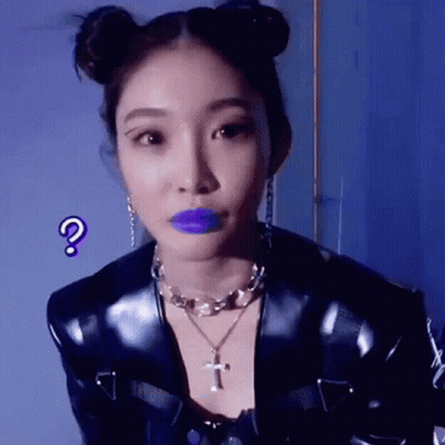 A Woman With Purple Lipstick And Buns On Her Hair Is Wearing A Black Jacket And A Necklace . GIF