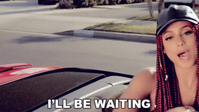 A Woman With Red Braids Is Sitting In A Car With The Words I 'Ll Be Waiting Above Her GIF