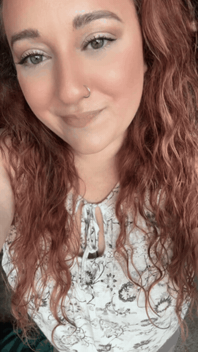 A Woman With Red Curly Hair And A Nose Ring GIF