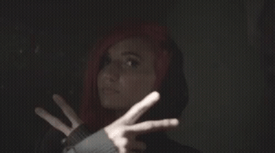 A Woman With Red Hair And A Black Hoodie Is Making A Peace Sign GIF