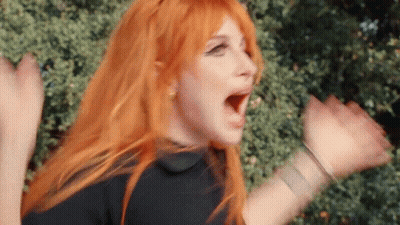 A Woman With Red Hair And A Black Shirt Is Screaming With Her Mouth Open . GIF