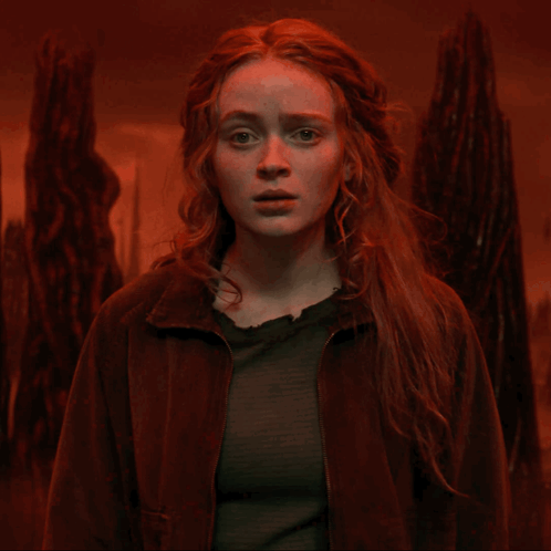 A Woman With Red Hair And A Brown Jacket Looks At The Camera GIF