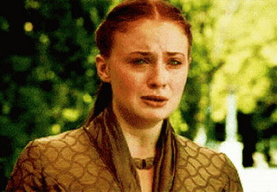 A Woman With Red Hair And A Scarf Around Her Neck Is Crying . GIF