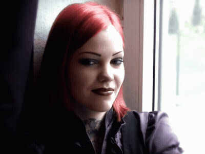 A Woman With Red Hair And A Tattoo On Her Neck Looks Out A Window GIF