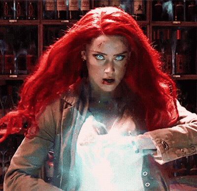 A Woman With Red Hair And Blue Eyes Is Standing In Front Of A Shelf Of Wine Bottles . GIF